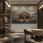 A large rectangular wall art piece featuring a textured stone-like background with a circular tree-of-life motif in the center, displayed above a dining table in a modern interior setting.