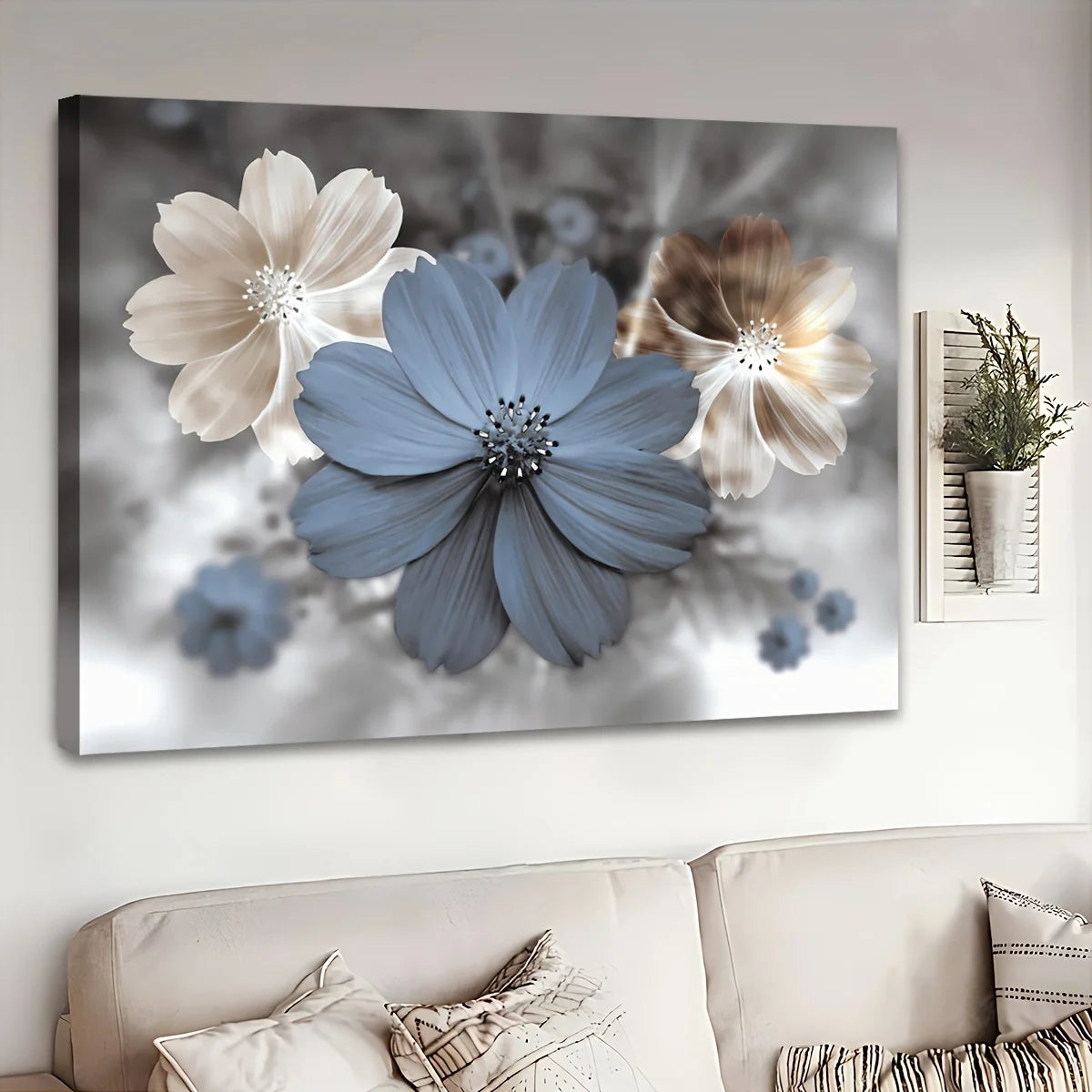 A rectangular wall art canvas showing three stylized flowers in blue, cream, and taupe against a soft gray floral background, displayed above a beige sofa in a living room setting.