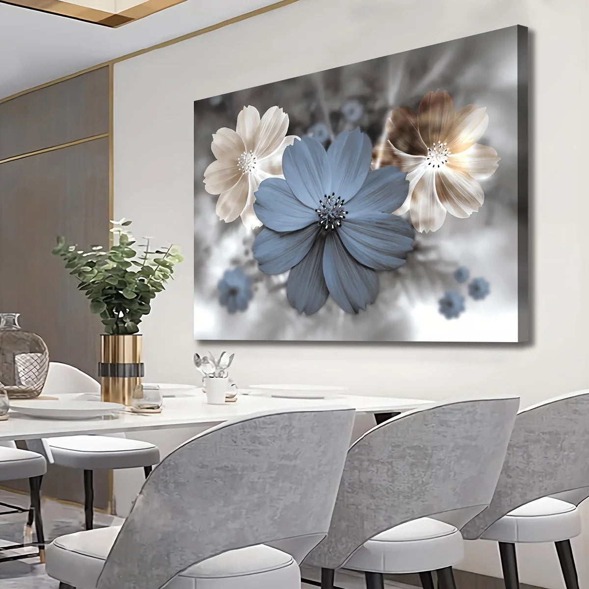 A large rectangular wall art print showing stylized flowers in blue, cream, and taupe tones, displayed above a dining table in a modern interior with gray chairs and a vase.