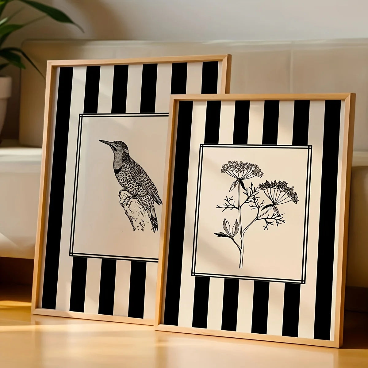 Two framed artworks with black and white designs of a bird and plant on a striped background.