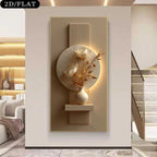 A modern wall art piece featuring a circular beige stone relief with white floral motifs and dried botanical stems in a small vase, mounted on a vertical rectangular panel with integrated warm lighting. The artwork is shown hanging in a contemporary interior hallway with a staircase and shelving visible.