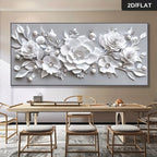 Large rectangular wall art featuring a 3D-style white floral design with layered roses, leaves, and pearl-like accents on a light gray background, displayed above a dining table in a modern interior. A small badge in the top-right reads 2D/FLAT.