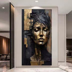 A large wall art piece featuring a stylized female face in metallic gold and dark charcoal tones, displayed in a modern interior hallway with marble flooring and glass walls.