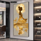 A vertical wall art print featuring a golden silhouette of a meditating woman against a large moon and abstract gold brushstrokes, displayed in a modern interior hallway next to a wine cabinet.