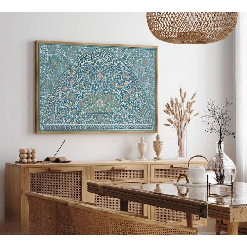 A framed wall art print featuring an intricate turquoise and blue Islamic-style arch pattern, displayed in a warm, modern boho dining room setting above a wooden credenza.