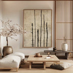 A large framed wall art print with vertical black brushstrokes on a textured beige background, displayed in a serene, minimalist Japanese-style living room with a low wooden table, cushions, and a blooming cherry blossom tree.