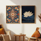 Two framed wall art prints displayed side-by-side on a white wall in a cozy living room setting. The left print features a detailed, symmetrical floral mandala pattern in warm orange, red, and cream tones on a dark blue background, enclosed in a light wood frame.
