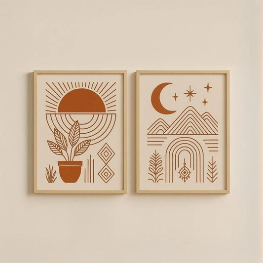 Two framed minimalist art prints with warm terracotta illustrations hang side by side on a cream wall. The left print shows a sun, plant, and geometric shapes, and the right print shows a crescent moon, stars, mountains, and arches.