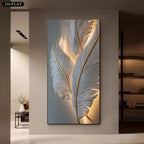 A vertical wall art piece featuring large illuminated white feathers with gold veining, displayed in a modern interior hallway setting.