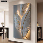 A vertical canvas wall art print featuring large illuminated white feathers with gold veins, displayed on a beige wall in a modern living space. A black '2D/FLAT' label is visible in the top-left corner.