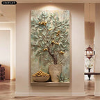 A large vertical wall art piece depicting a potted olive tree with gold fruits in a textured stone-style pot, displayed in a modern hallway setting with wood floors and warm lighting.