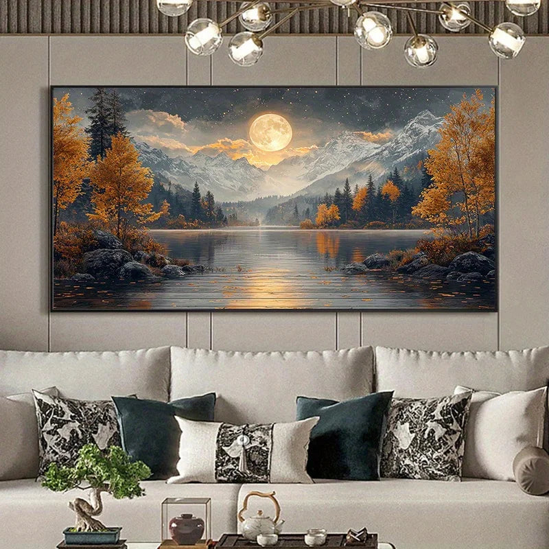 A large rectangular wall art print depicting a moonlit mountain lake landscape with golden trees, is displayed above a white sofa in a modern living room setting.