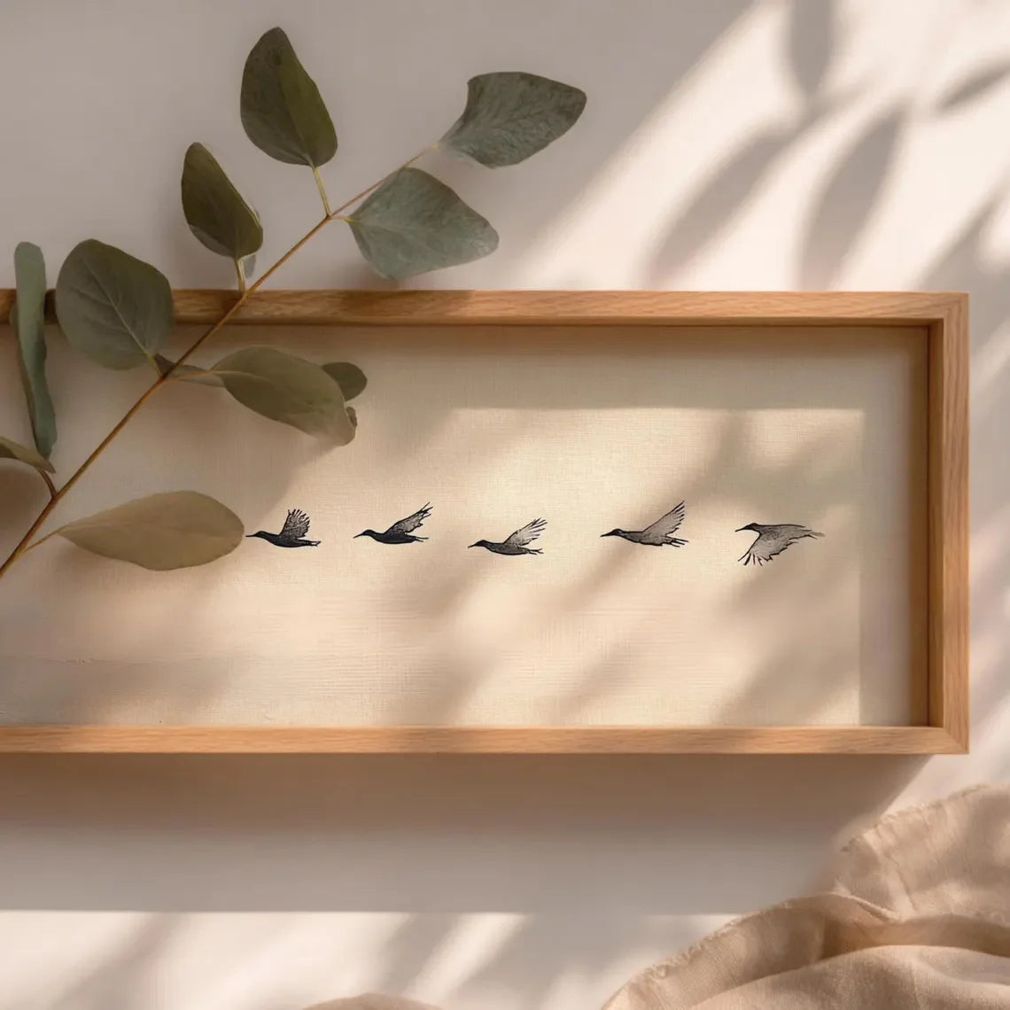 Artwork of five birds in flight on a beige background, with a branch of eucalyptus leaves on the left.