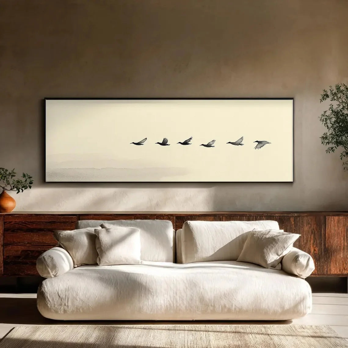 Beige sofa in a room with a framed artwork of birds on a beige wall.