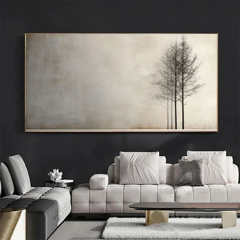 A large wall art piece hangs above a light gray sofa in a modern living room. The artwork shows a minimalist beige background with three dark, bare trees on the right side.