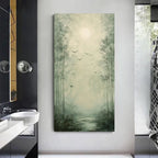 A vertical canvas wall art print depicting a misty forest path with tall trees, flying birds, and a glowing sun, displayed on a light gray wall in a modern bathroom setting.
