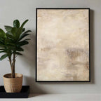 Abstract art print in a black frame on a wall next to a potted plant.