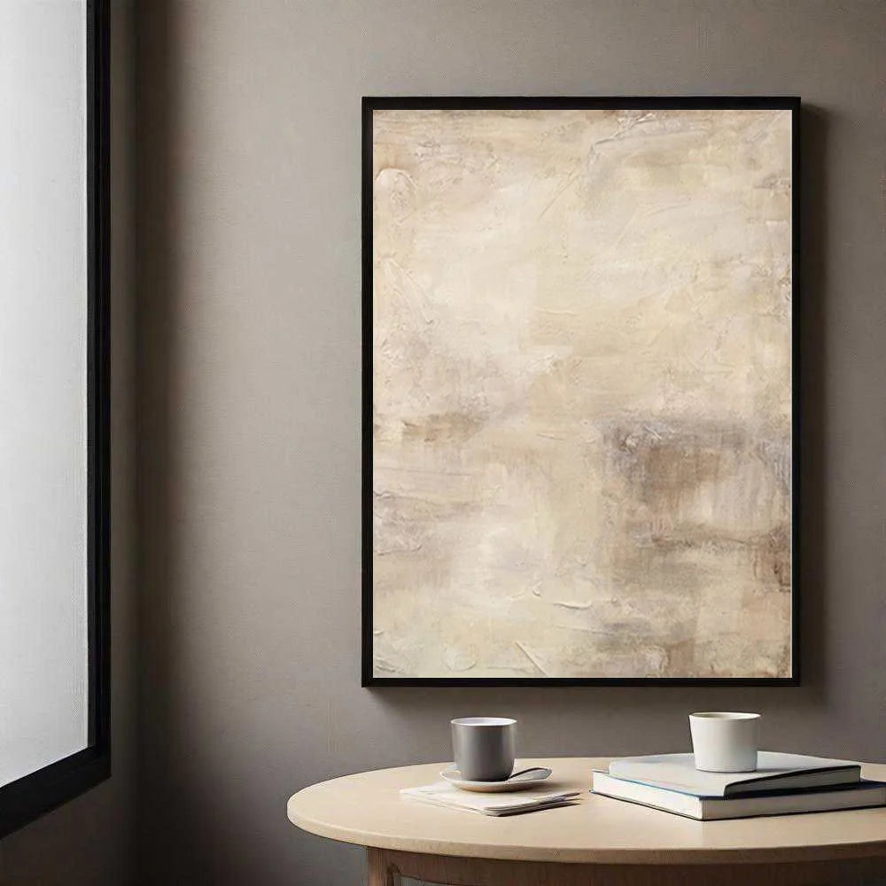 Abstract art print on a wall above a round wooden table with a cup and books.