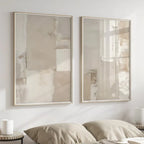 Two framed abstract paintings on a wall above a bed.