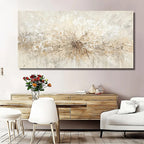A large rectangular abstract wall art piece with a textured radial burst in cream, beige, and white tones, displayed above a wooden console in a styled living room with white chairs, a sofa, and a vase of flowers.