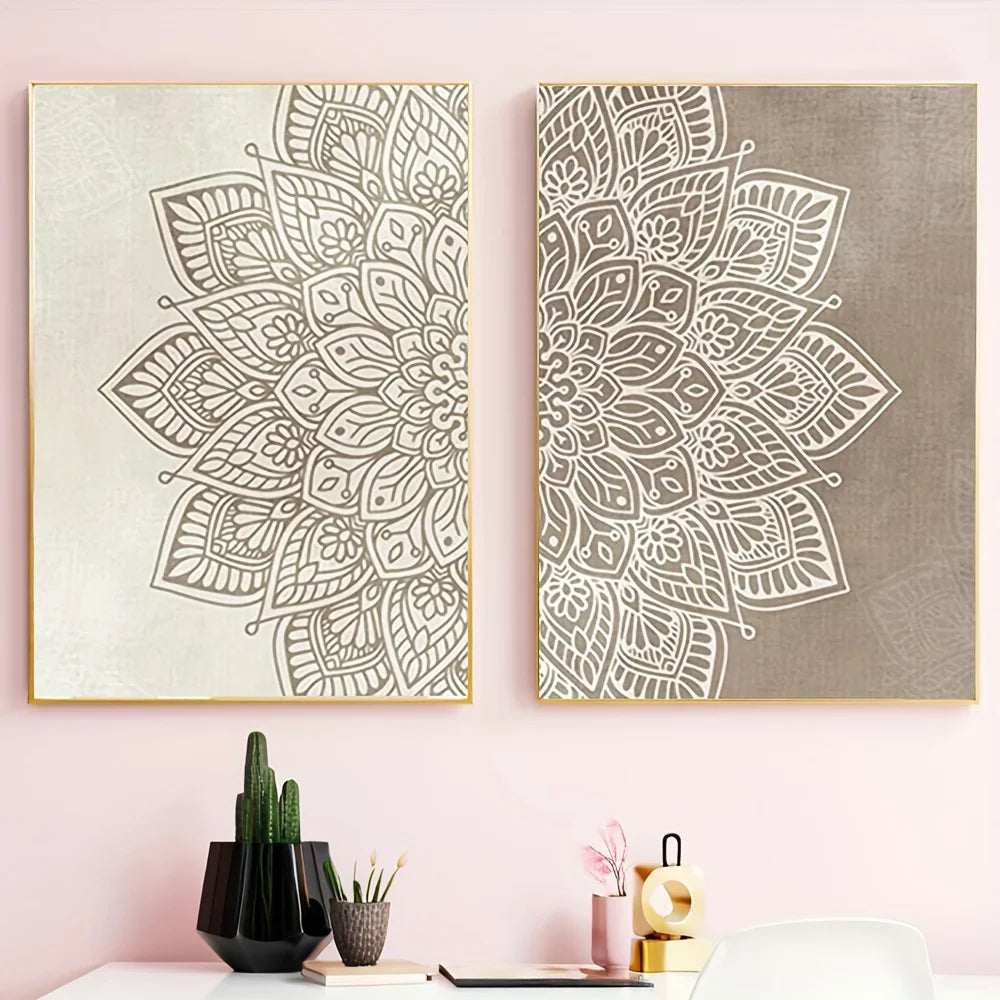 Two vertical framed wall art prints with intricate mandala designs hang on a light pink wall above a desk with small decor items including a cactus, books, and a pink candle holder.
