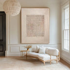 A large square abstract canvas print with a textured grid pattern in soft beige, cream, and muted pink tones, displayed on a wall in a bright, modern living room above a light wood daybed with white cushions.