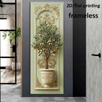 A vertical wall art print featuring a potted olive tree with gold fruit and ornate beige scrollwork on a pale green background, shown mounted in a modern interior doorway. Text in the top right reads '2D/flat printing frameless'.