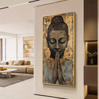 A vertical wall art print featuring a serene Buddha face with hands in prayer, displayed in a modern living room setting.