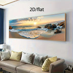 A large panoramic beach sunset canvas print displayed on a white wall above a beige sofa in a modern living room. The print shows ocean waves, rocks, and golden sand under a warm sky, with the text '2D/flat' above it.