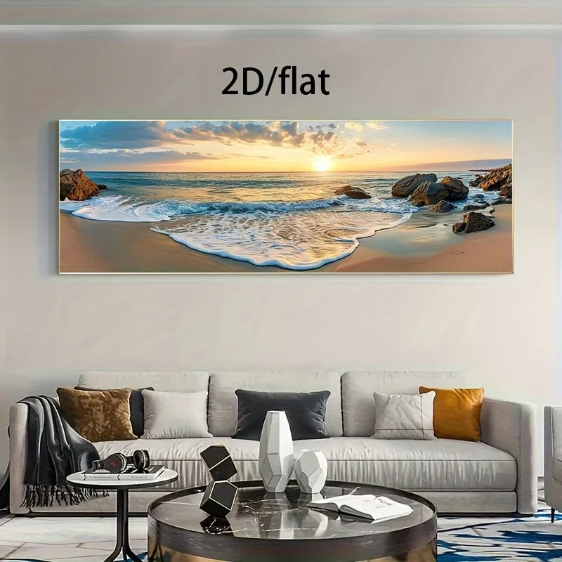 A large panoramic canvas print of a beach sunset displayed on a wall above a modern light gray sofa in a living room. The print shows ocean waves washing onto a sandy beach with rocks and a glowing sunset sky.