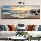 A large panoramic framed wall art print showing a beach sunset with ocean waves, rocks, and golden sky, displayed above a modern sofa in a living room. The text '2D/flat' appears at the top of the image.