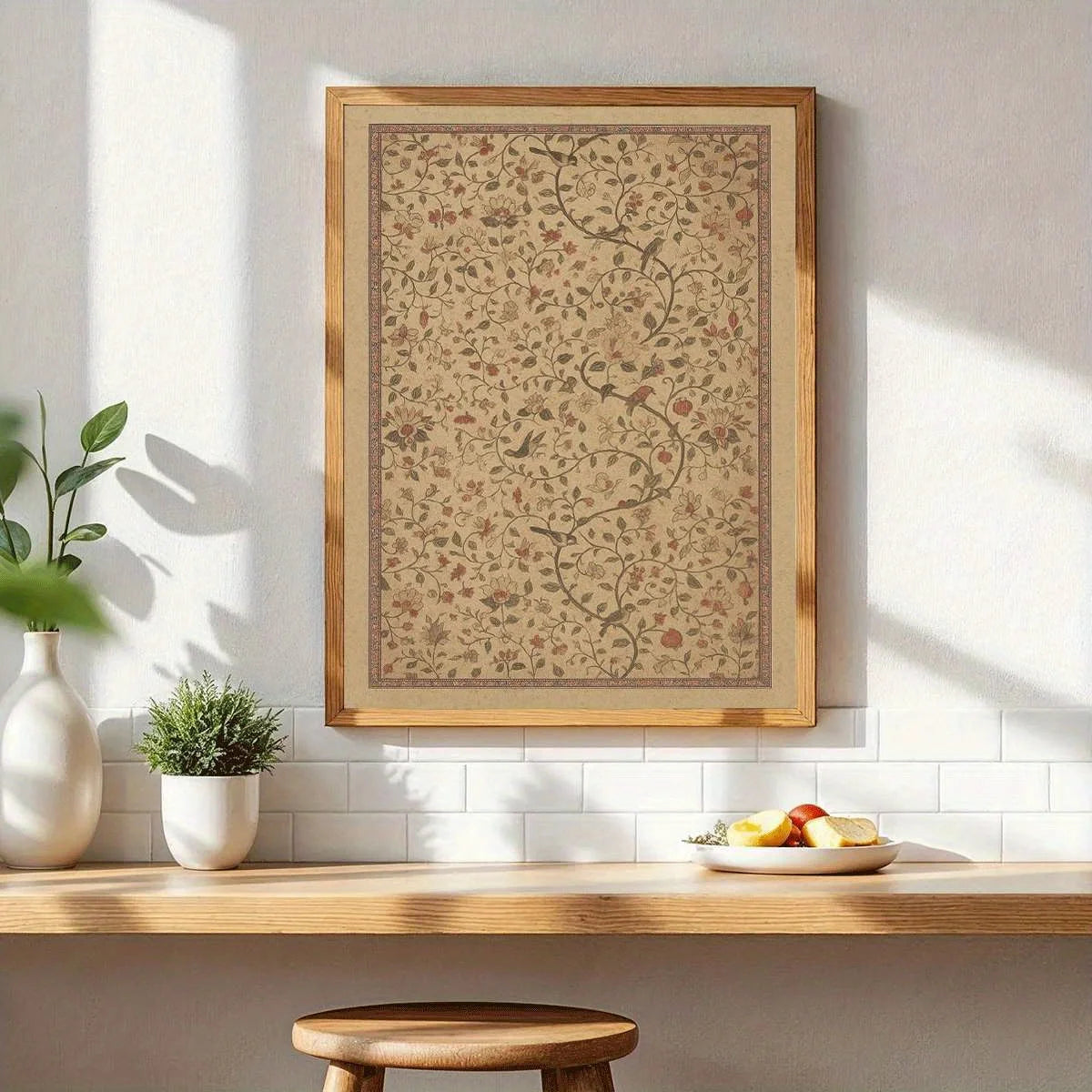 A framed botanical art print with a beige background, delicate floral patterns, and a light wood frame, hanging on a white wall above a wooden shelf with decorative plants and a fruit plate.