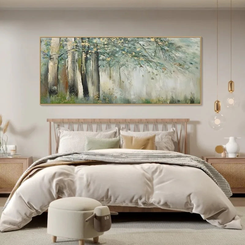 A large horizontal canvas painting of a misty forest with tall trees in soft green, gray, and beige tones, displayed above a neatly made bed in a modern, neutral-toned bedroom.
